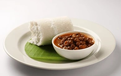 Kerala breakfast at Café Malabar Singapore — steaming puttu cylinder with kadala (black chickpea) curry.
