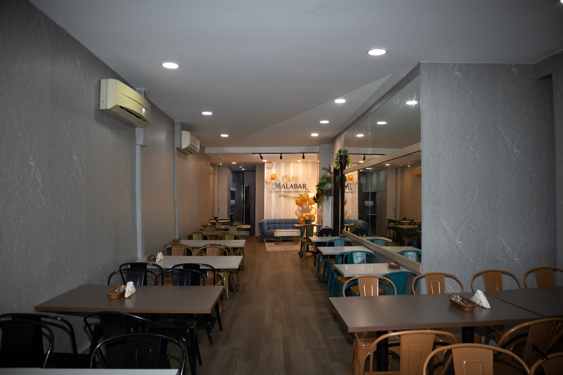 Long dining room inside Café Malabar with wooden floors, warm lighting and set tables