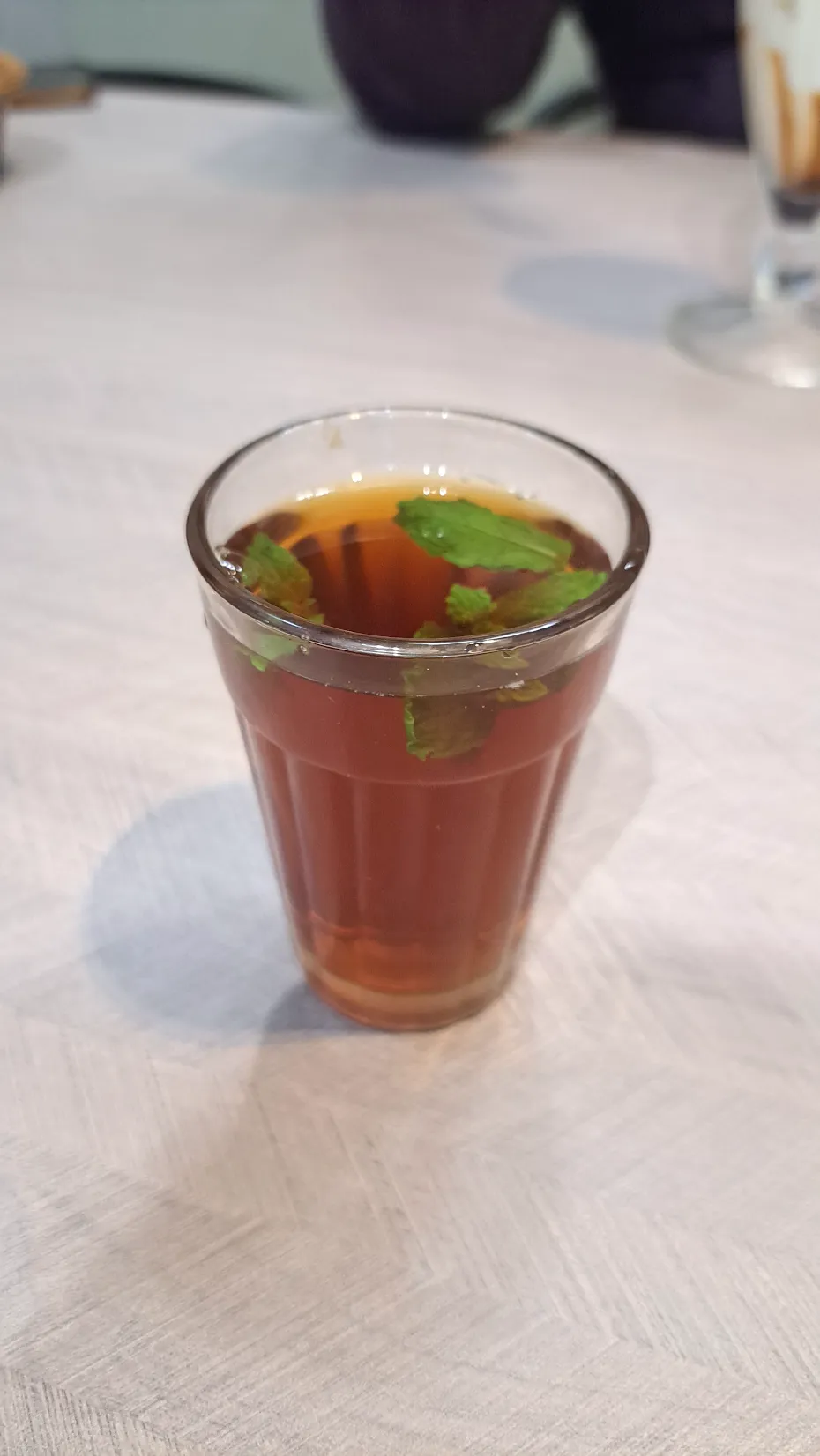 Glass of hot Sulaimani — black Malabar tea with lime, clove and mint — at Café Malabar's chaya counter, Arab Street Singapore.